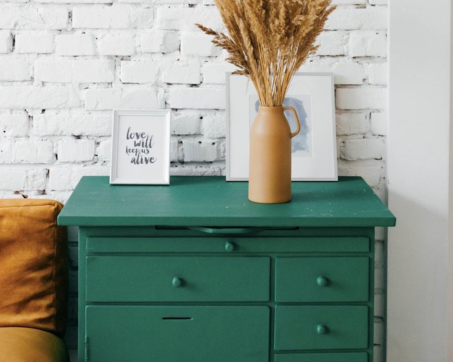 Image of a vase placed on top of pastel green table with drawers